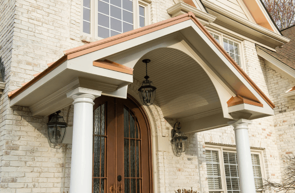 AFTER up close of copper gable portico with white columns on white brick home