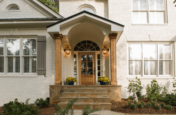 AFTER installation of gabled roof portico with wooden columns on white brick home up close