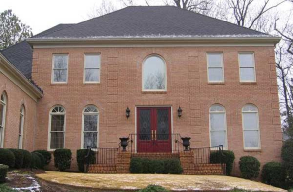 BEFORE installation of arched roof portico on brick house with red double doors