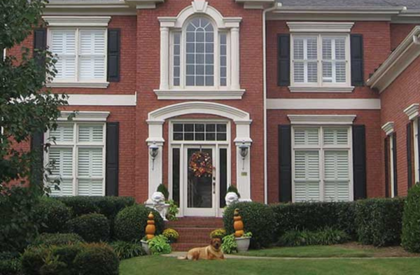 BEFORE installation of arched roof portico with brick home and black shutters on long windows