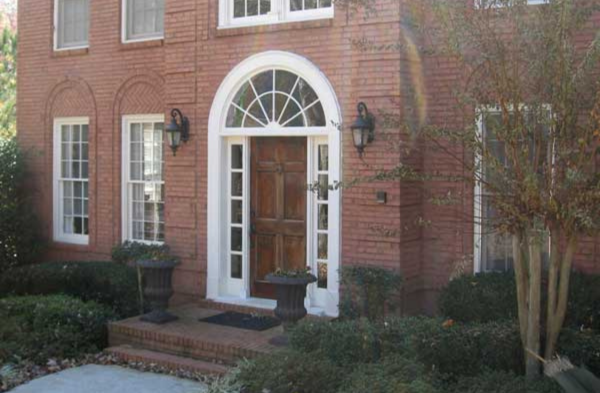 BEFORE installation of arched roof portico on brick house with wood door and white trim