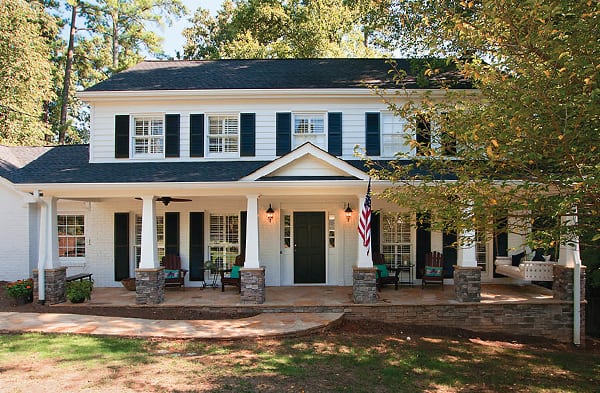 AFTER traditional front porch and stone floor on square white home with black shutters