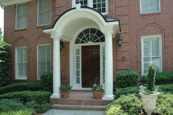 arched portico with thick circular columns on brick house up close