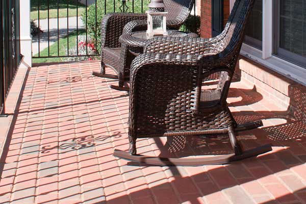 brick floor front porch with brown wicker furniture