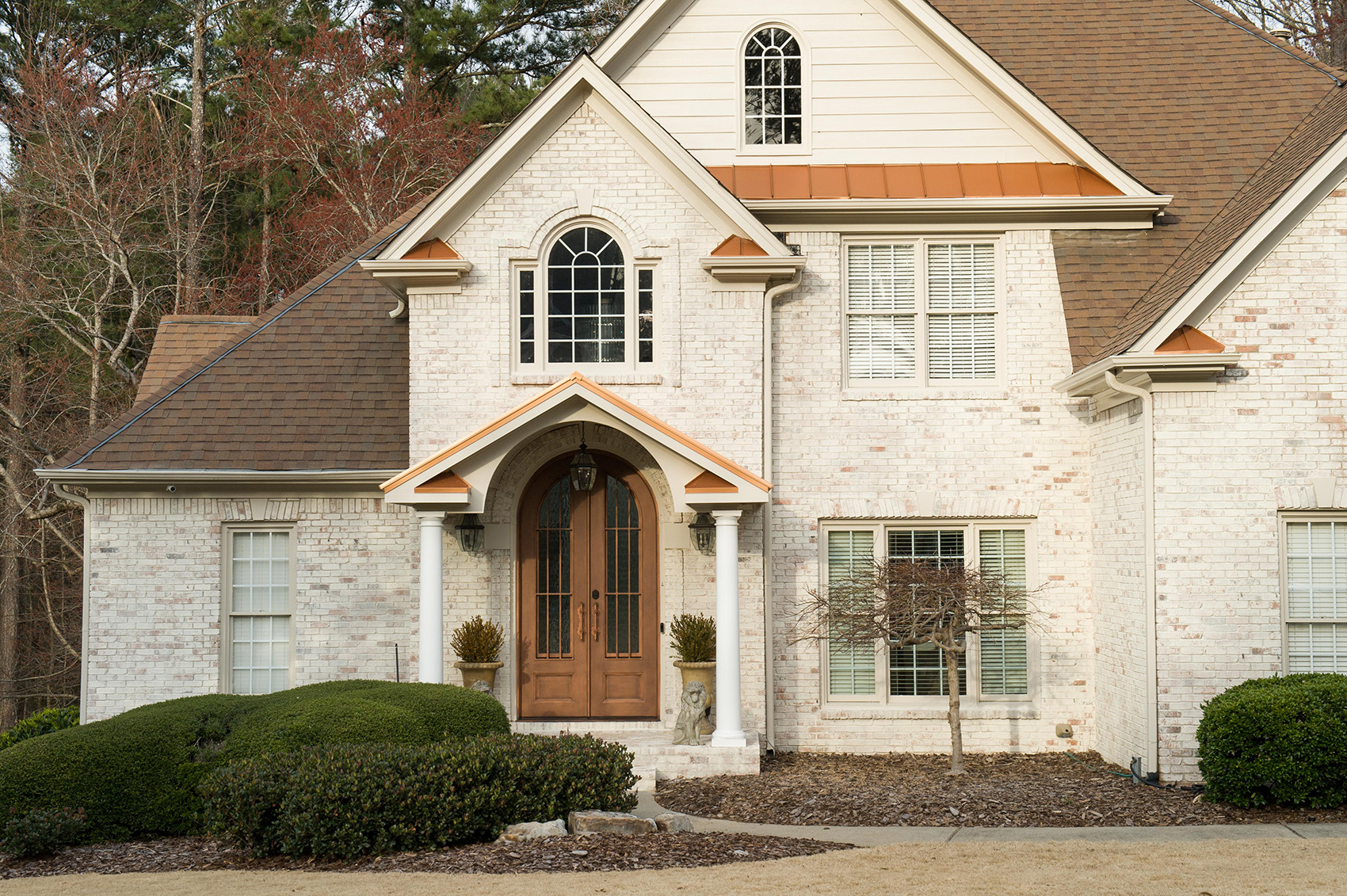 copper gable portico with white columns on white brick home