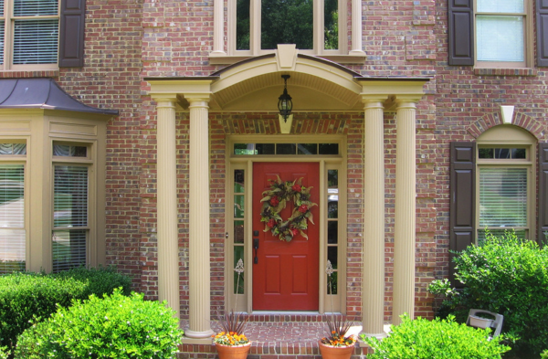 AFTER installation of arched roof portico on brick house with red door front view