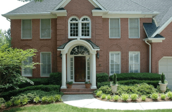 AFTER installation of portico with thick circular columns on large brick home