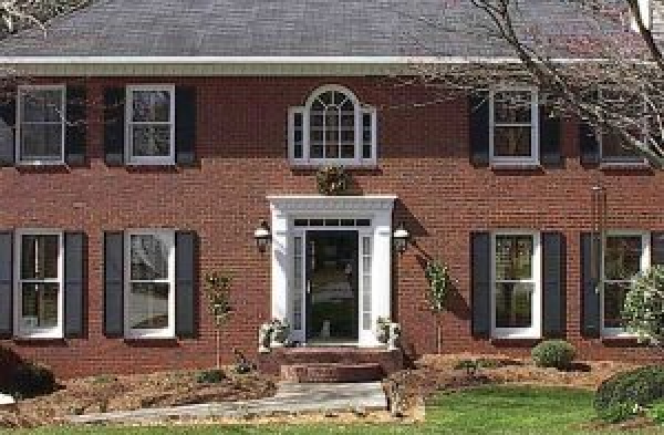 BEFORE installation of hip roof portico on brick house with black shutters and glass door