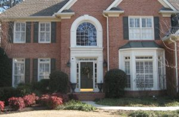 AFTER installation of gabled roof portico on brick home with black shutters and bay window