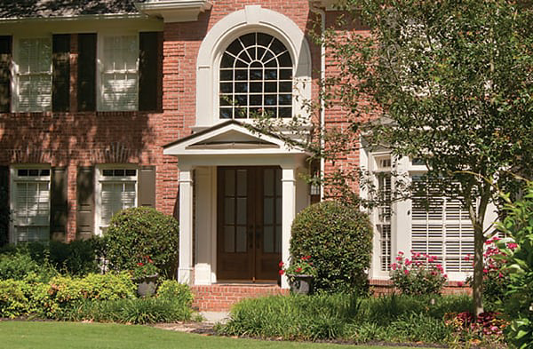 AFTER installation of gabled roof portico on brick home with black shutters and double wood door