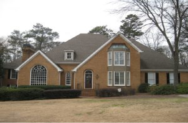 BEFORE installation of gabled roof portico on large brick home with black shutters and round top window and door