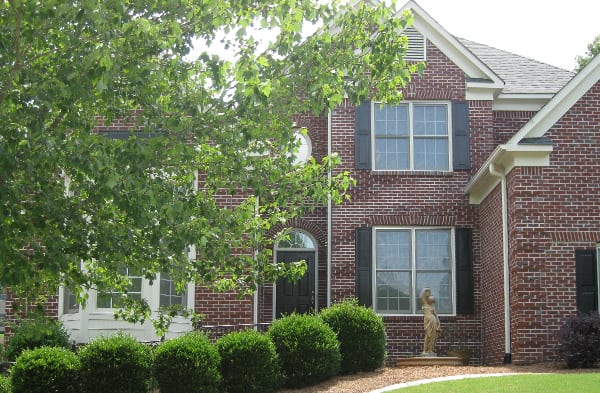 BEFORE installation of front porch of brick home with white bay window tree in front of house on left