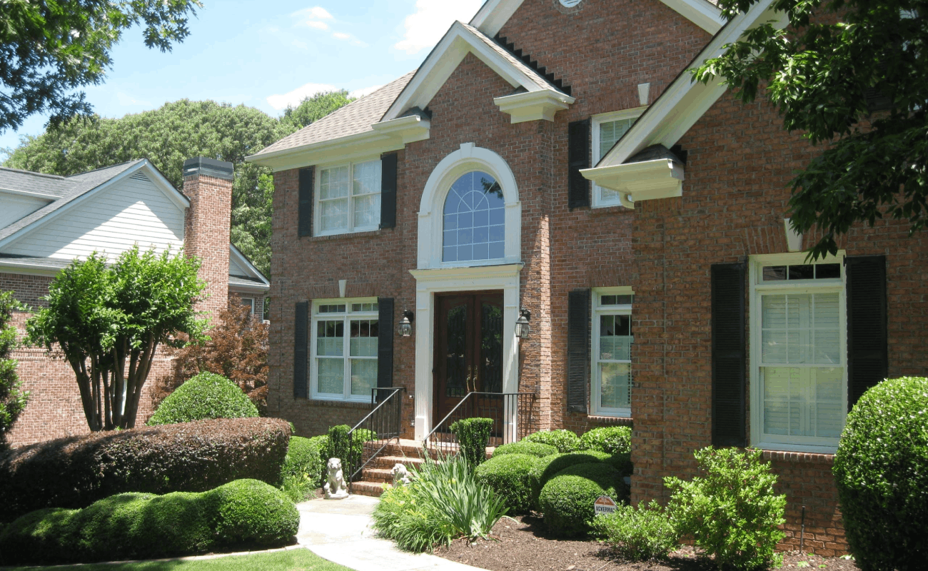 BEFORE installation of front porch with white columns of large brick home side front view