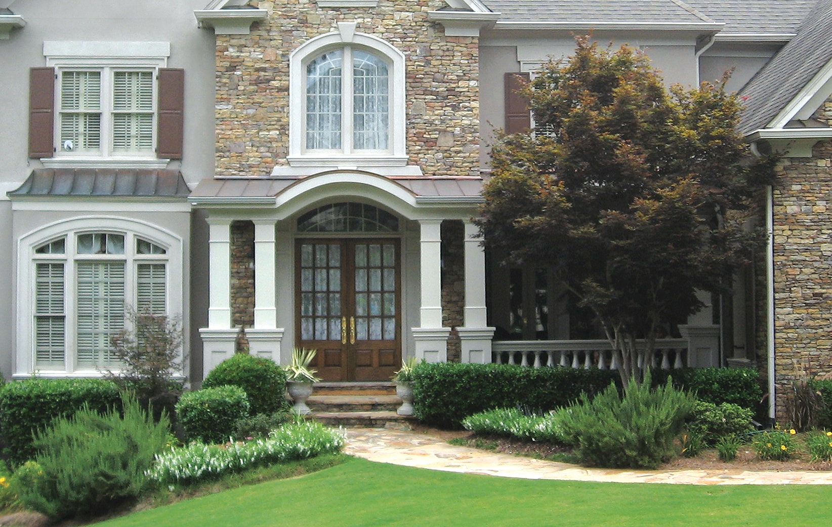 AFTER front porch with thick square white columns and double wooden door up close