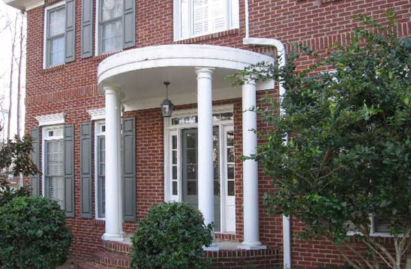 DURING installation of round portico with white columns on brick home