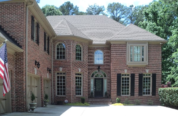 BEFORE installation of front porch with tan columns of brick home with brown door