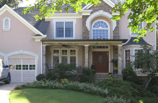 AFTER installation of stone front porch on beige house with white trim and brown door