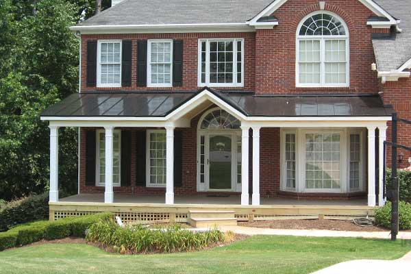 AFTER installation of traditional front porch with white columns on square brick home with white window trim