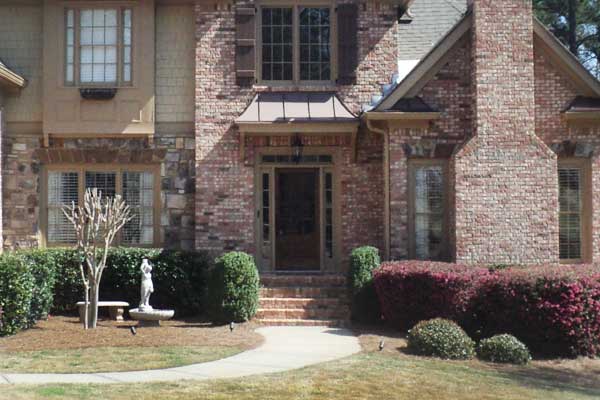 BEFORE installation of portico on large multi-colored brick home up close view