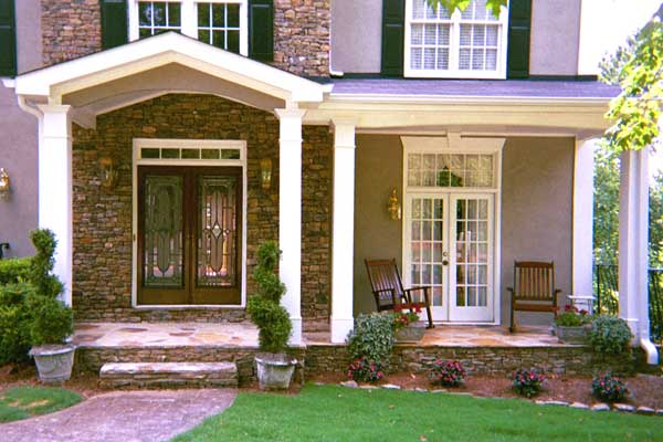 AFTER installation of traditional half front porch on beige and stone home with brown double doors