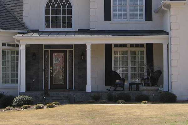 AFTER installation of traditional half porch on large beige home with black shutters