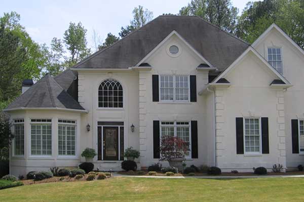 BEFORE installation of traditional half porch on large beige home with black shutters