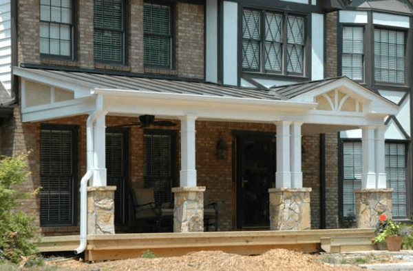 Tudor home half porch white columns with stone base