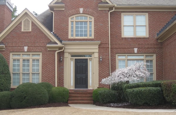 BEFORE photo of shed roof portico on brick home with beige installation