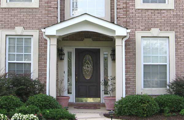 AFTER installation of gabled roof portico on brown door of brick home