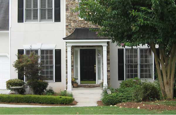 AFTER installation of hip roof portico on stone and white house with black shutters