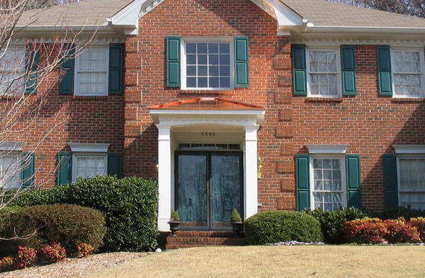 AFTER installation of hip roof portico on brick house with green shutters