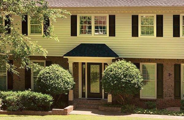 AFTER installation of hip roof portico on white shingled and brick house with black shutters