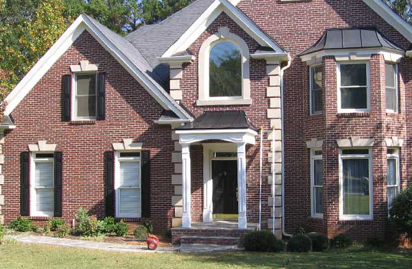 AFTER installation of hip roof portico on brick house with black shutters and white trim