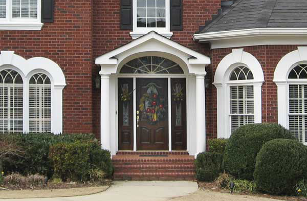 AFTER installation of a gable roof portico on large brick house with round top windows