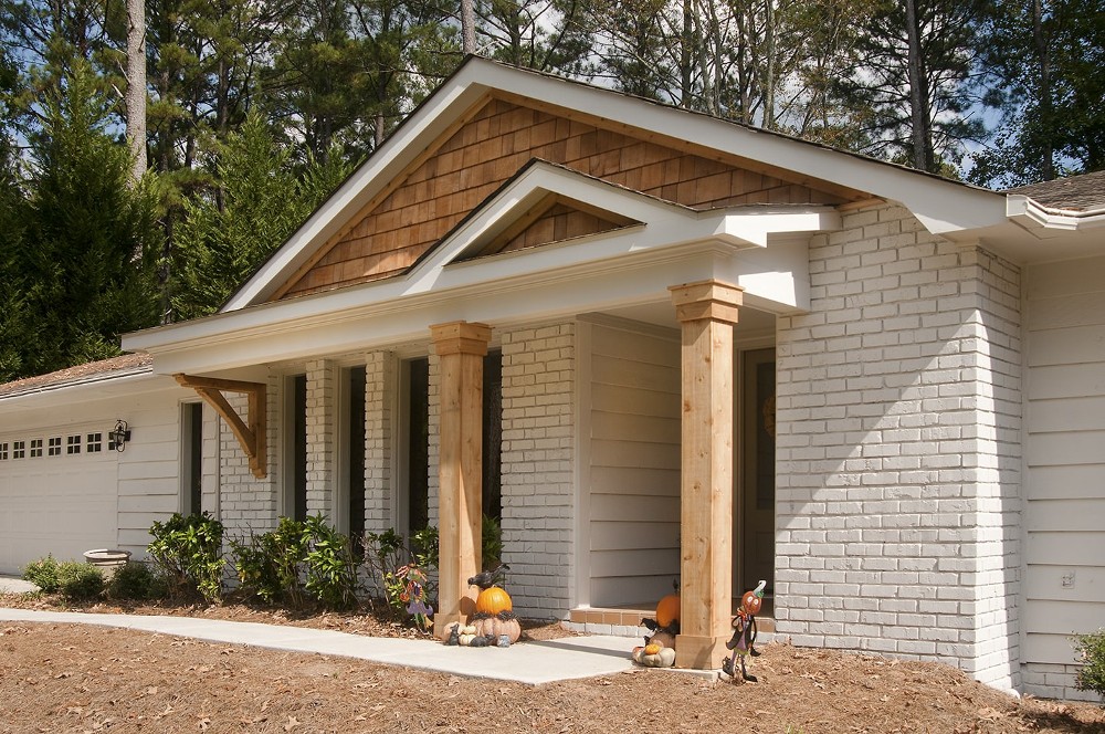 AFTER installation of gabled roof portico with with wooden columns on white brick rancher up close