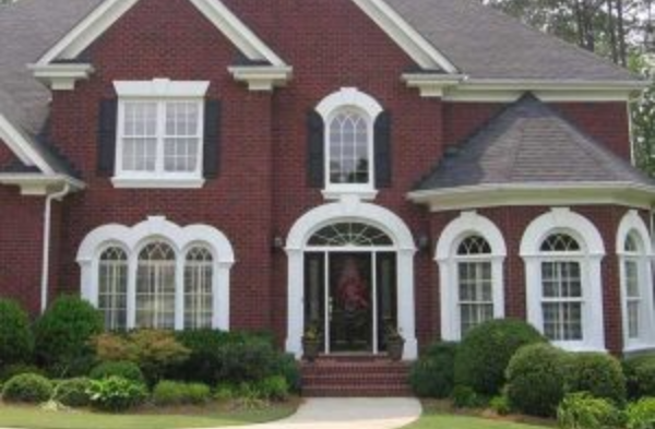 BEFORE installation of a gable roof portico on large brick house with round top windows