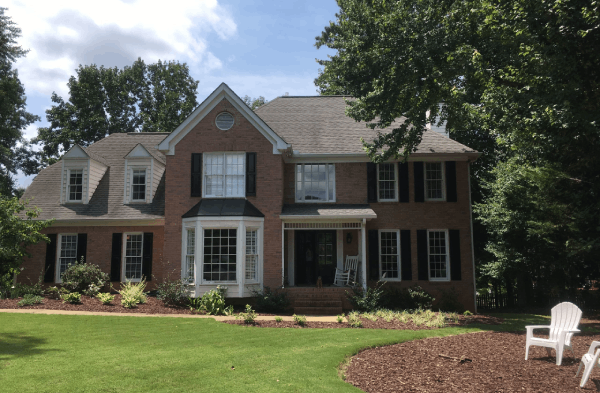 BEFORE installation of front porch on brick craftsman tudor home with adirondack chairs