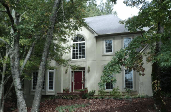 AFTER installation of stone front porch on large beige home with front trees