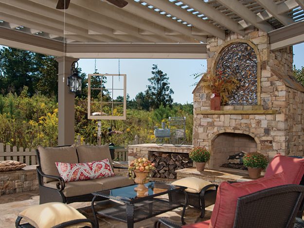 pergola over outdoor kitchen with furniture and stone fireplace