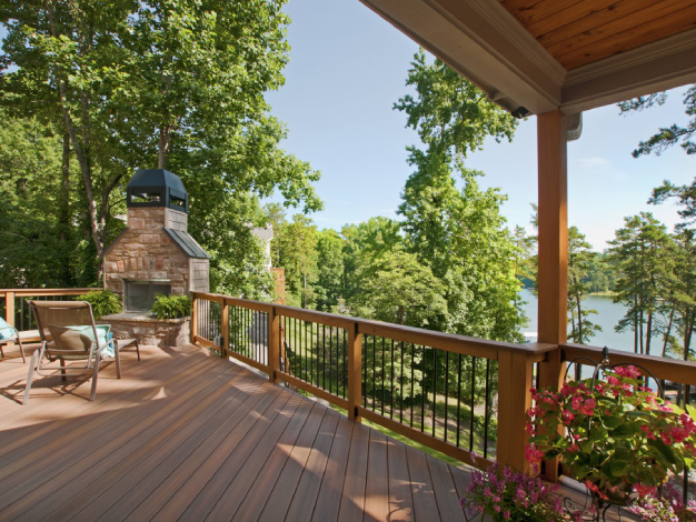 wooden open porch with table and chairs facing woods with stone outdoor oven