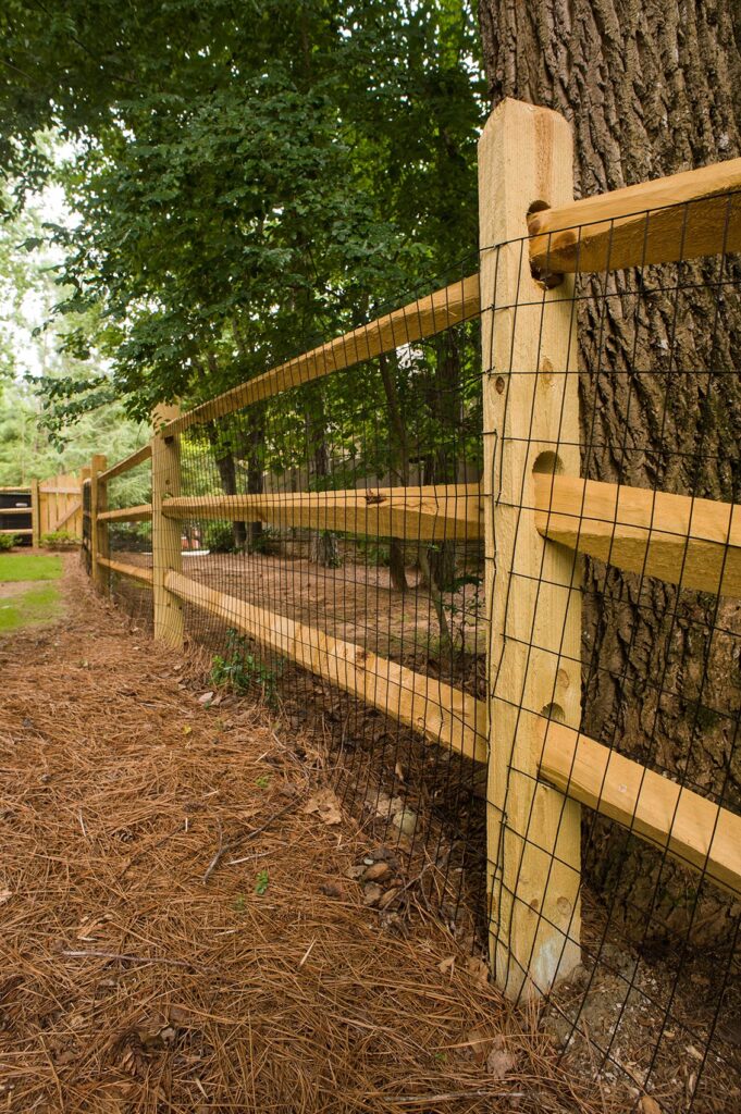 wooden split rail fence with metal barrier up close