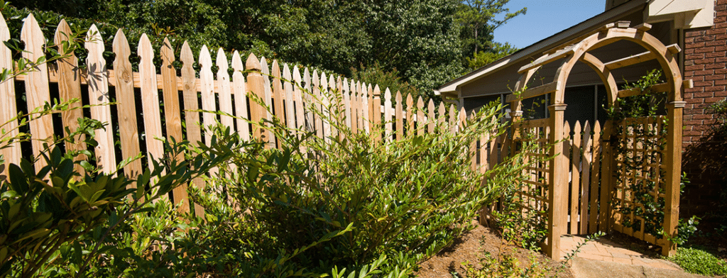 Wood picket fence with a gate and arched arbor in Johns Creek, Georgia.